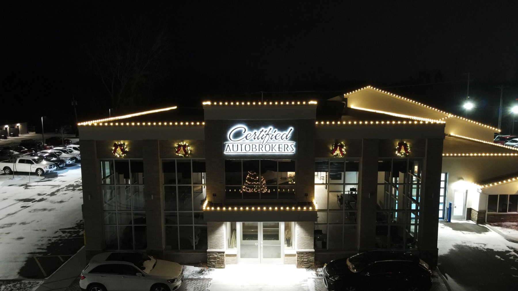 Warm-white roofline lights and illuminated wreaths at Certified Autobrokers