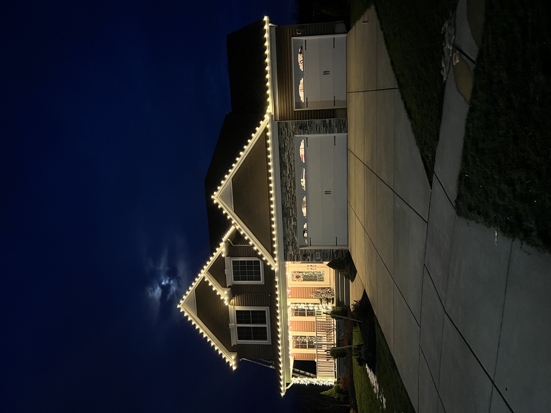 Warm-white lights outlining the roof peaks and front porch of a two-story home