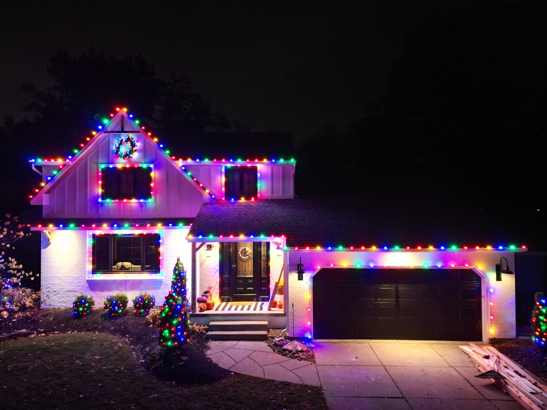 Multicolor holiday lights following the roof peaks of a two-story home at night