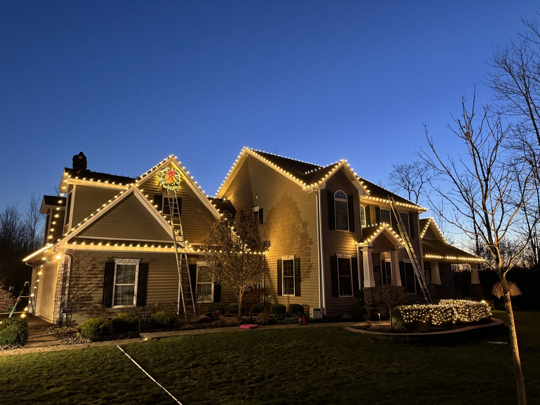 WNY Services holiday lighting installation with warm white rooflines and a wreath