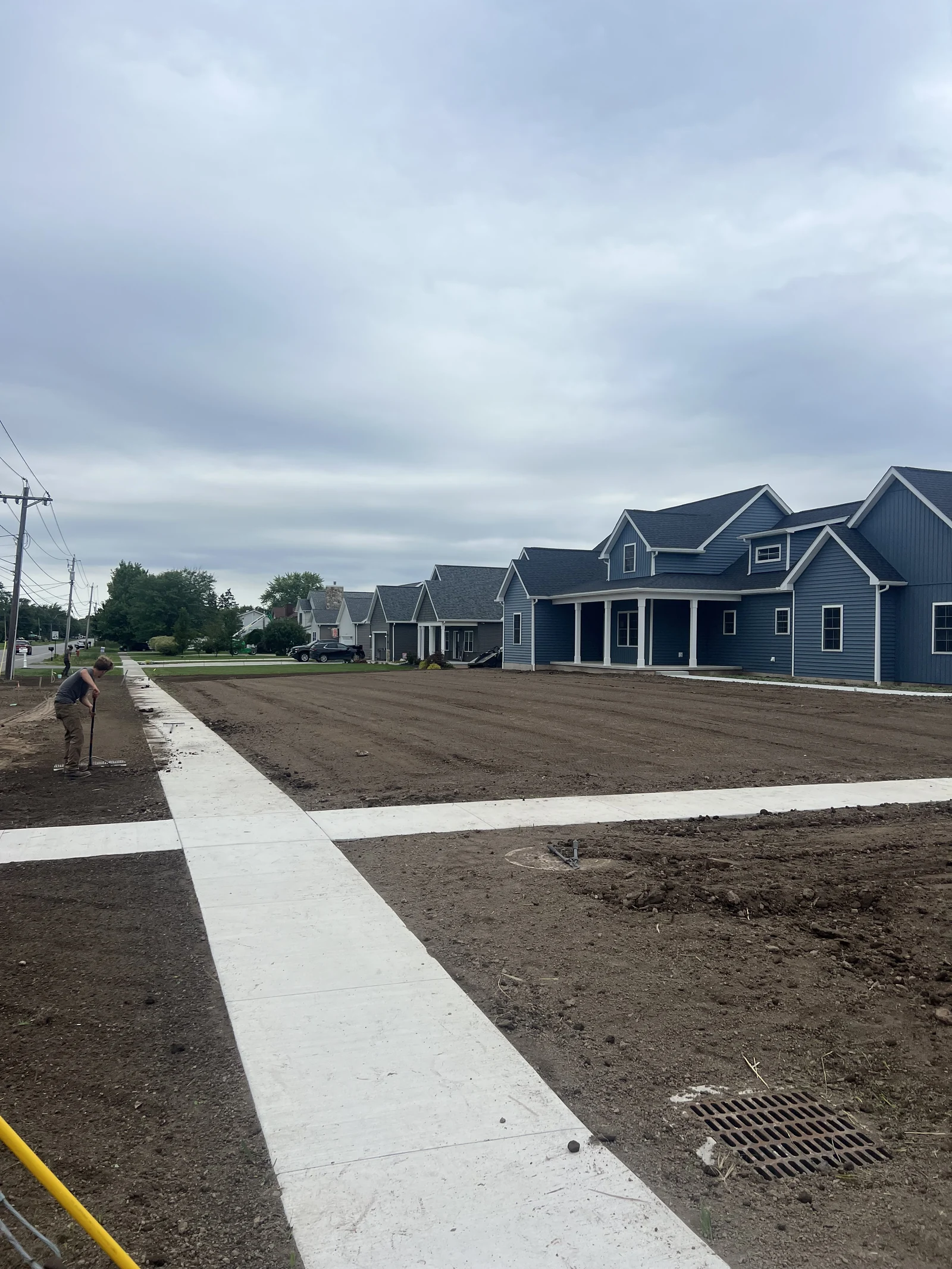 WNY Services crew member raking prepared soil beside the front walk of a townhome lawn
