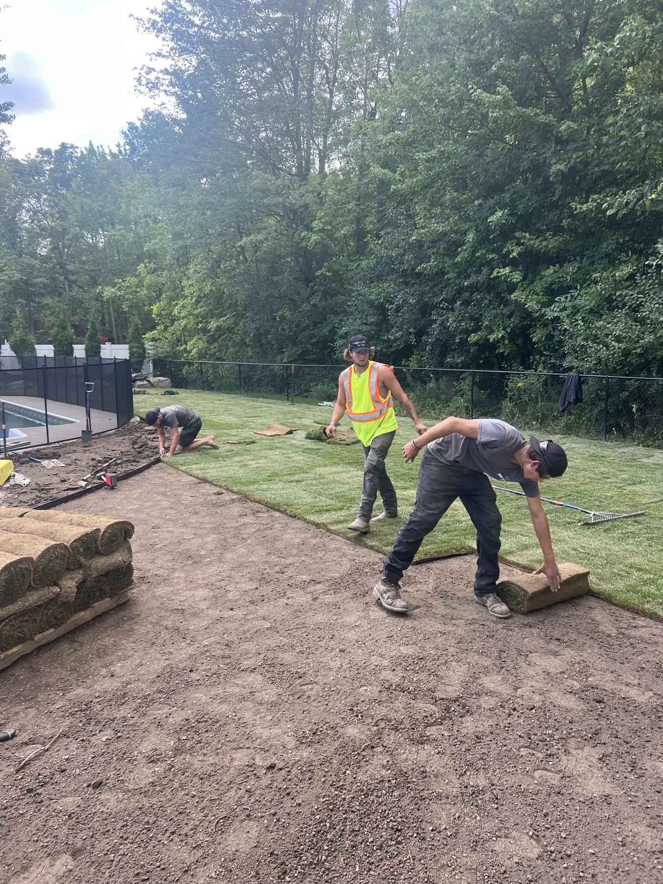 WNY Services crew laying fresh sod beside an existing pool